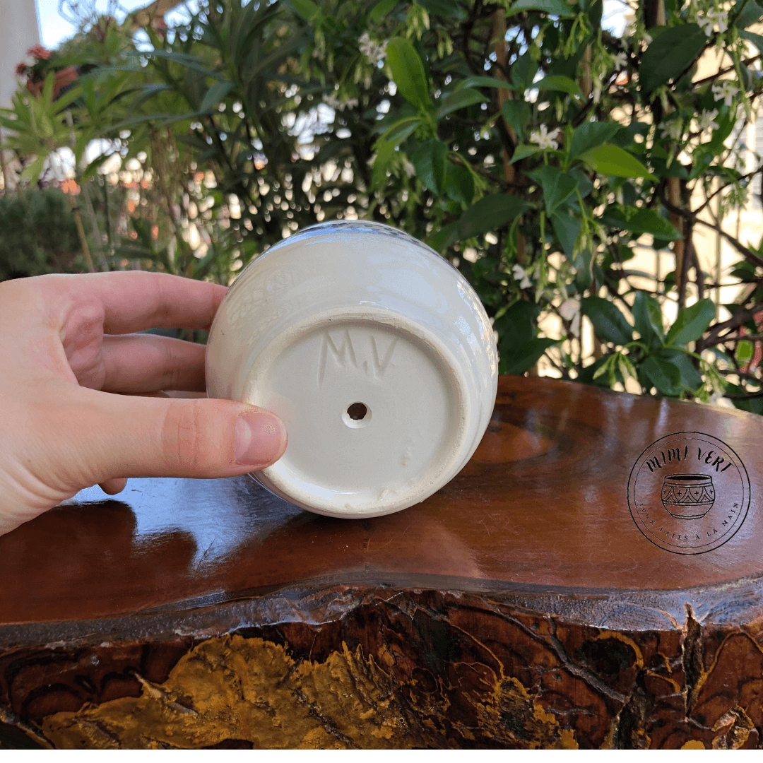 Pot en céramique fait à la main avec des motifs inspirés de l’artisanat marocain, posé sur une table en bois avec des plantes vertes en arrière-plan.