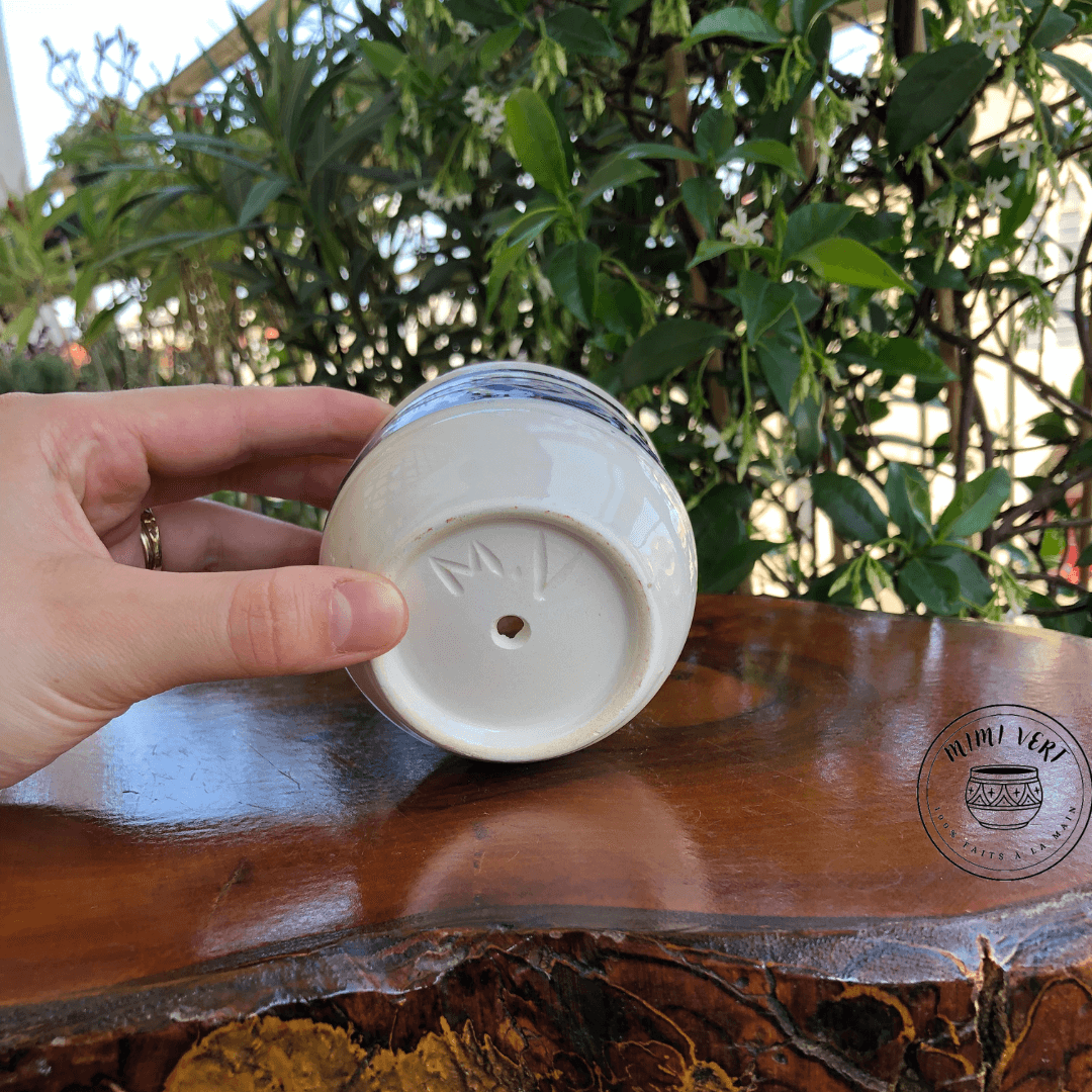 Pot en céramique fait à la main avec des motifs inspirés de l’artisanat marocain, posé sur une table en bois avec des plantes vertes en arrière-plan.