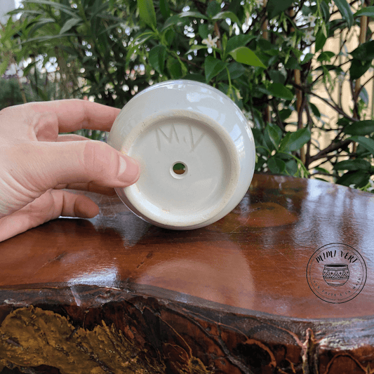 Pot en céramique fait à la main avec des motifs inspirés de l’artisanat marocain, posé sur une table en bois avec des plantes vertes en arrière-plan.